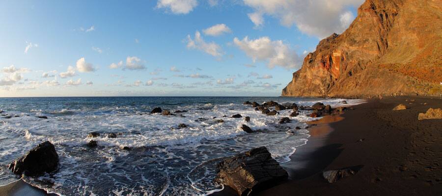 Relax on the beach next to copper cliffs at Playa Del Ingles. 